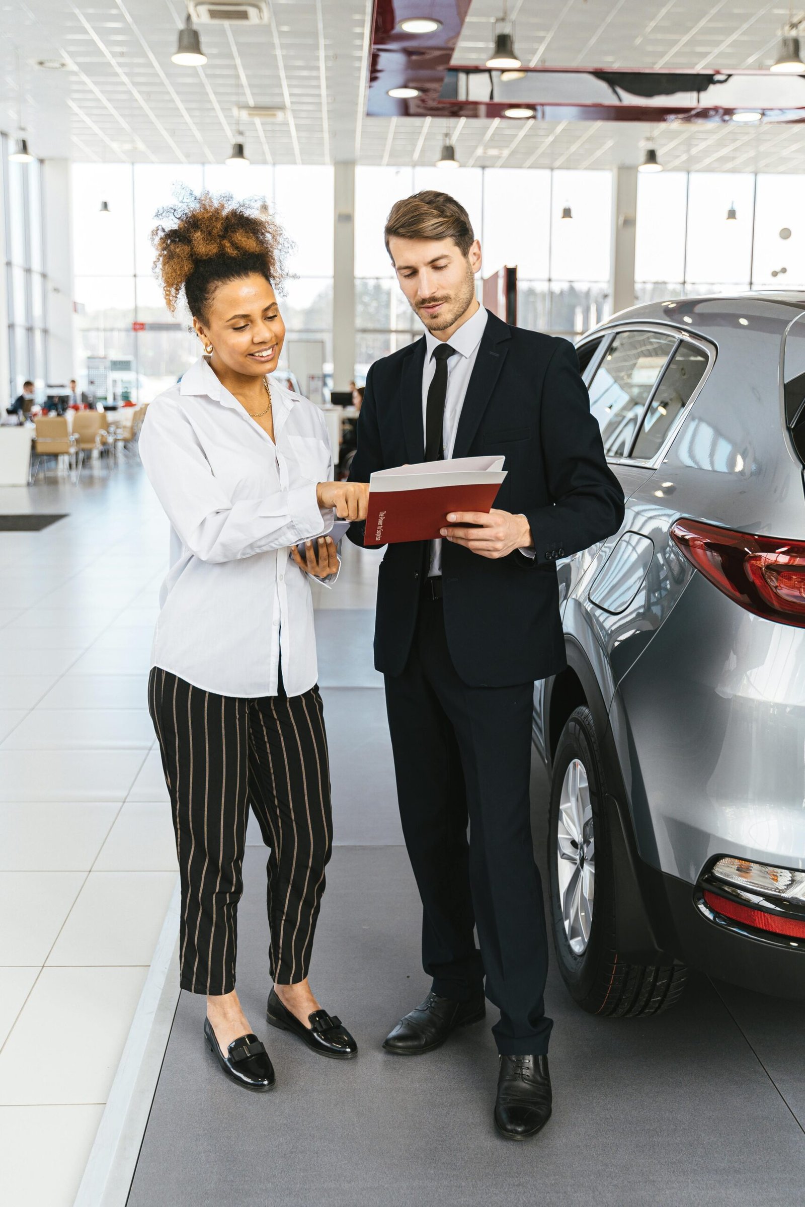 Man and woman discussing car purchase inside a modern dealership.